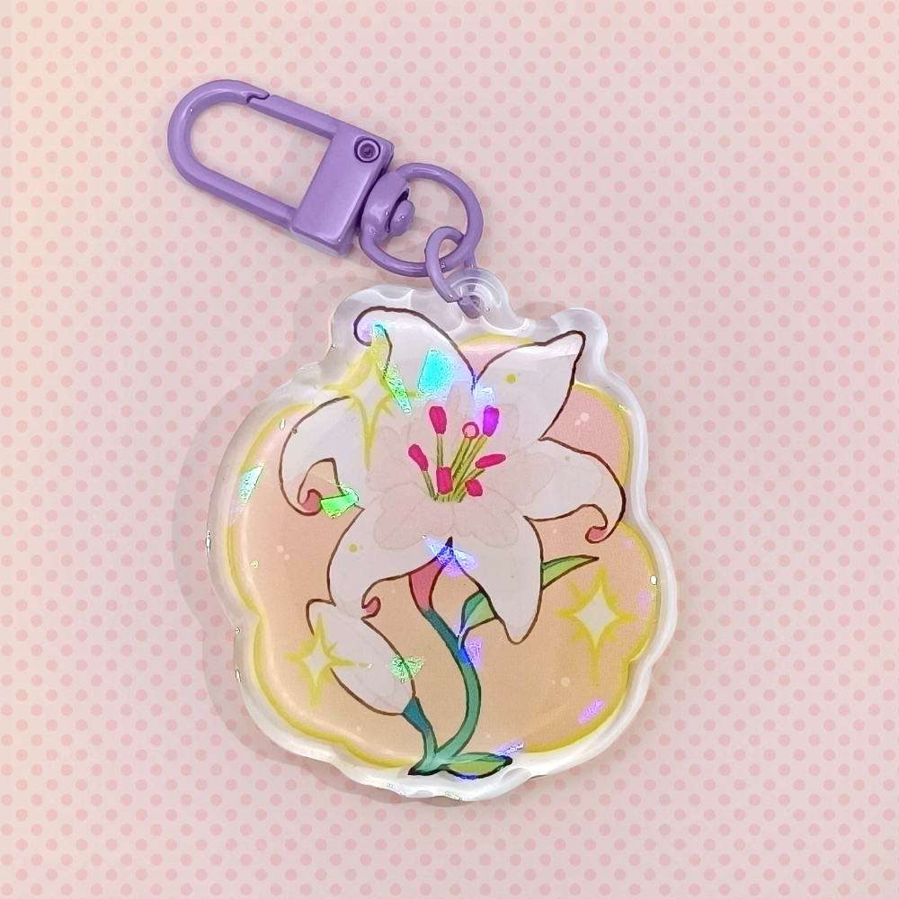 Lily charm on a peach background. The keychain itself is purple. The charm has a white Lily on an orange-yellow gradient, and is topped off with a holo shard texture.