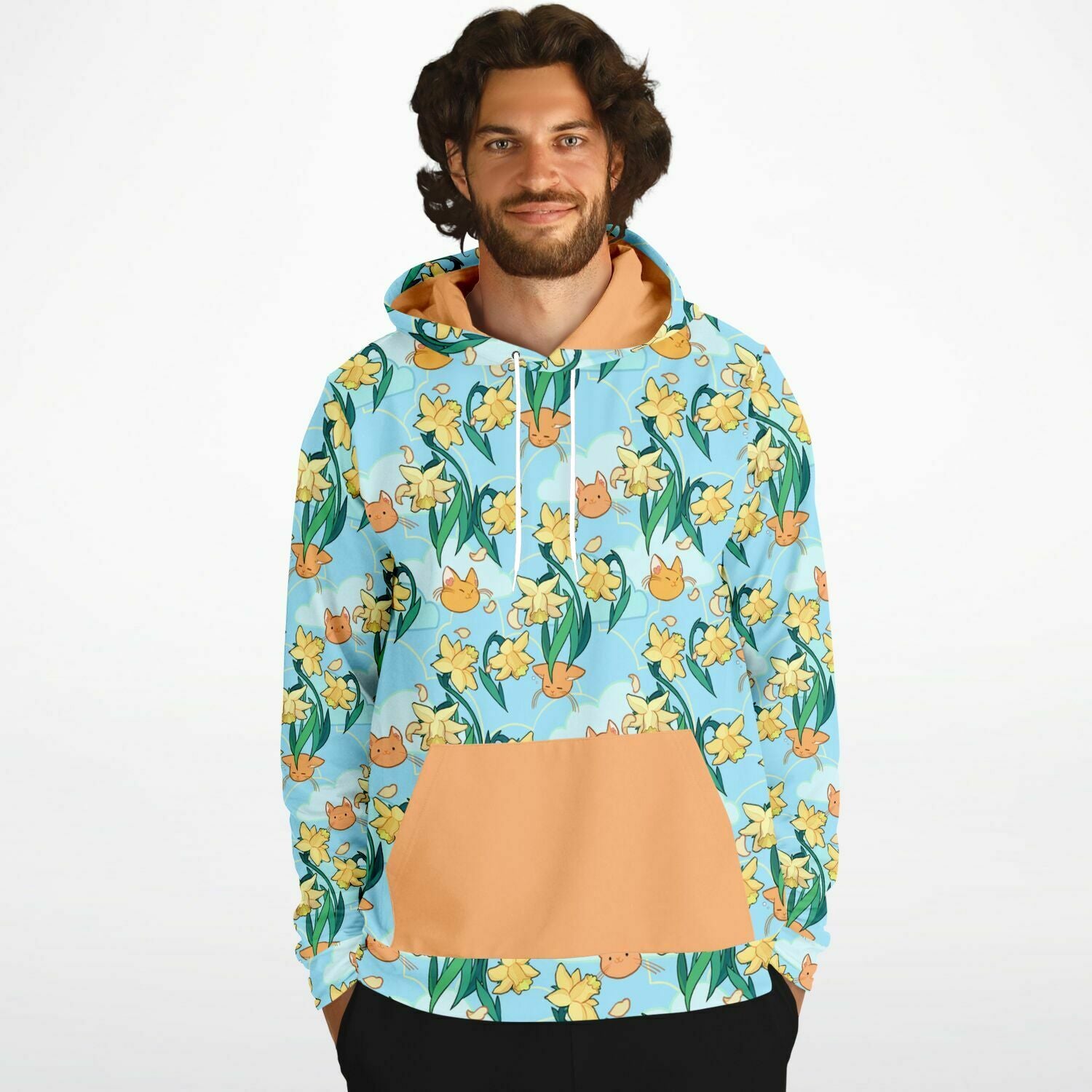 A model wearing a hoodie. The hoodie's pattern features cute cat faces and daffodils on a blue background. The pocket and lining of the hood are orange