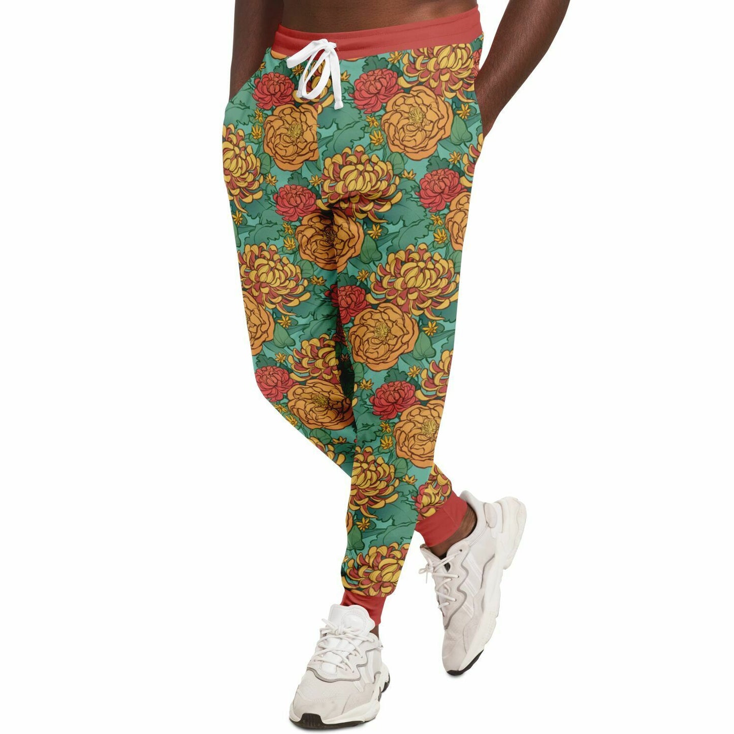 A model wearing joggers. The joggers' pattern features yellow and red chrysanthemums, and orange peonies on a green background. It has red cuffs.