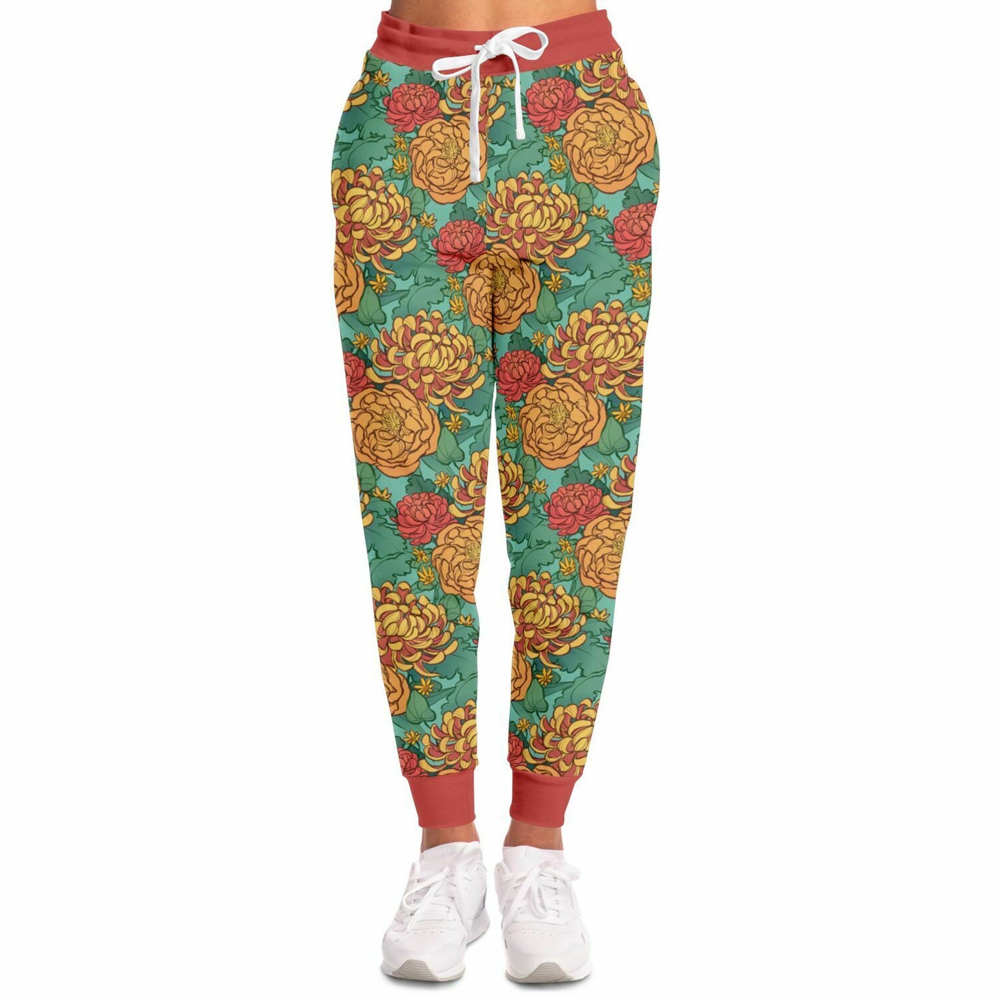 A model wearing joggers. The joggers' pattern features yellow and red chrysanthemums, and orange peonies on a green background. It has red cuffs.