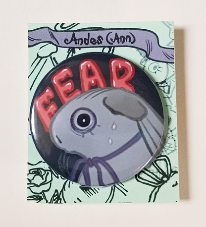 A Large button of a grey guinea pig with a purple ribbon. It has big fearful eyes, and some sweatdrops.   The background is  black and reads the word "FEAR" in red.