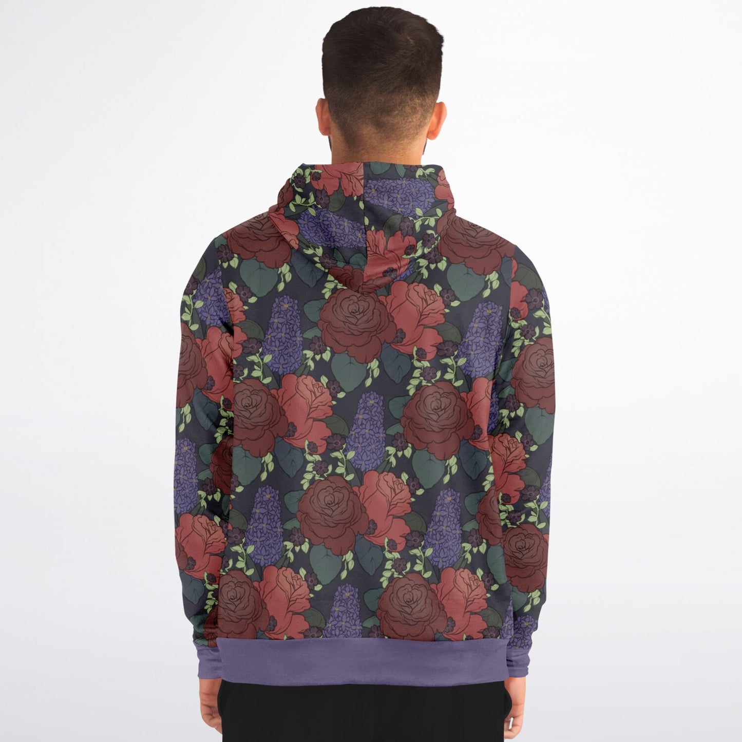 A model wearing a hoodie. The hoodie's pattern features red roses, purple hyacinths, and small black flowers on a dark grey background. It has a purple hem and cuffs