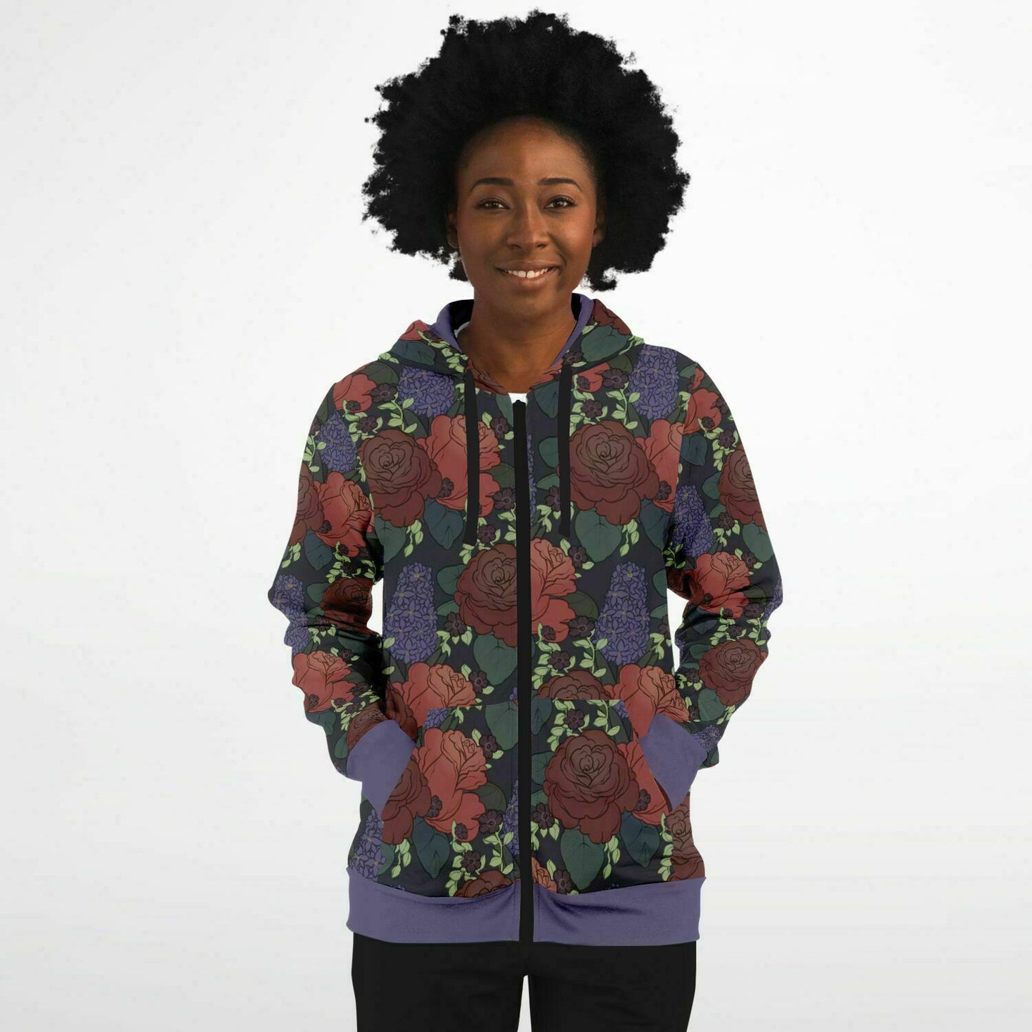 A model wearing a hoodie. The hoodie's pattern features red roses, purple hyacinths, and small black flowers on a dark grey background. It has a purple hem and cuffs