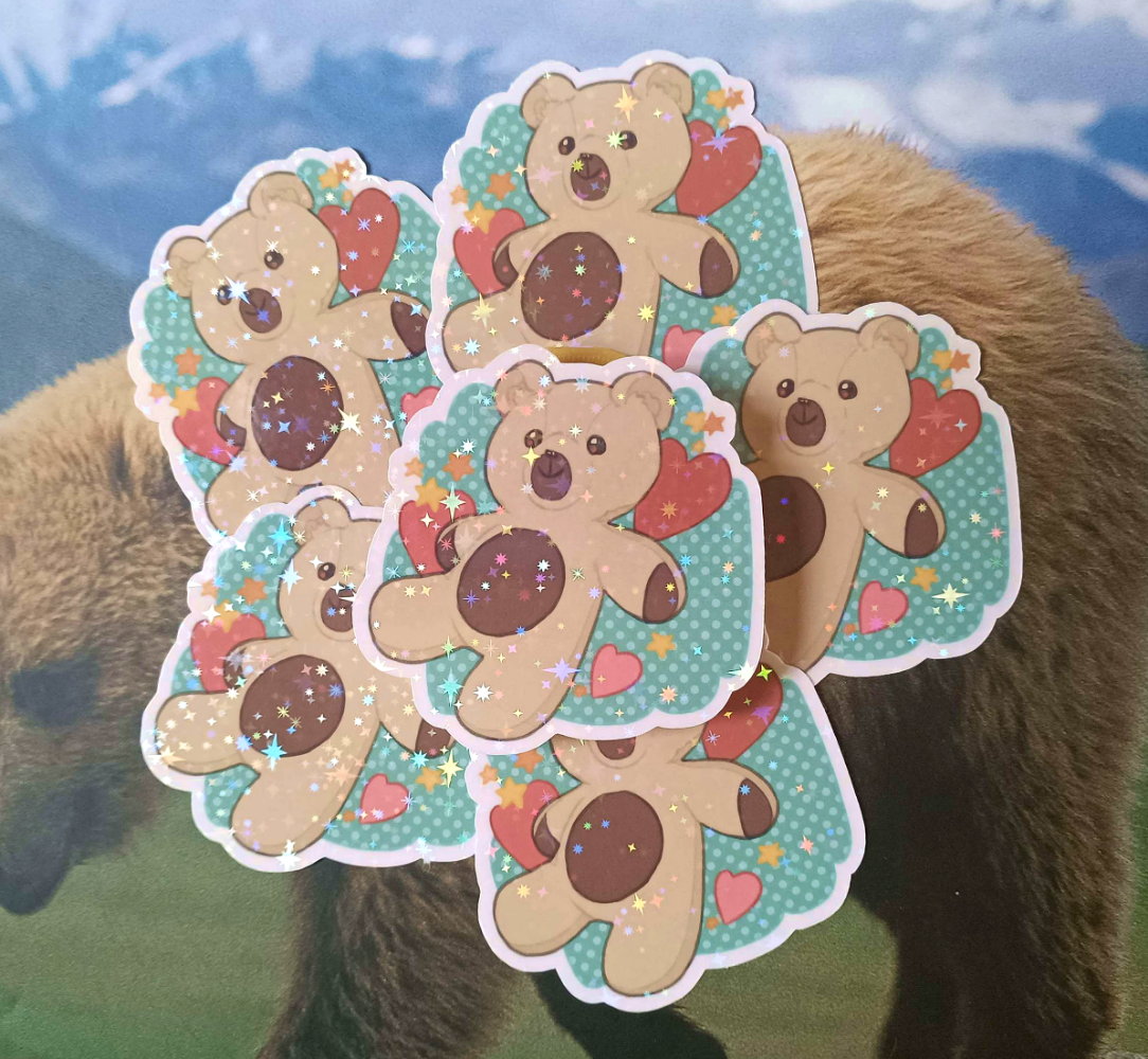 6 Teddy Bear stickers. It's a light brown bear with dark brown patches on its belly, snout, and hands. The background is green with light polka dots, and has hearts and stars on it. To top it off, there are holo stars on it.