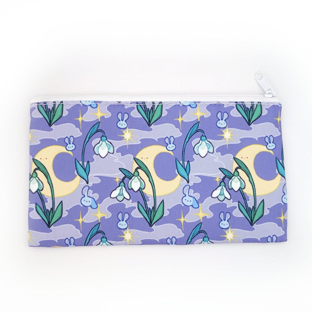 A pencil case. It is purple with a smoky background. It features stars, the moon, snowdrops, and cute bunny heads floating around.