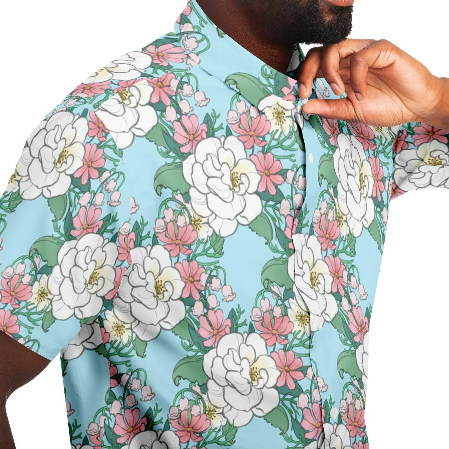 A model wearing a button down. The button down's pattern features white wild roses, pink cosmos, and lillies of the valley on a light blue background. it has a pink hem and cuffs.