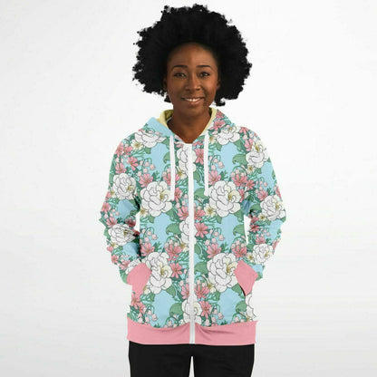 A model wearing a hoodie. The hoodie's pattern features white wild roses, pink cosmos, and lillies of the valley on a light blue background. it has a pink hem and cuffs.