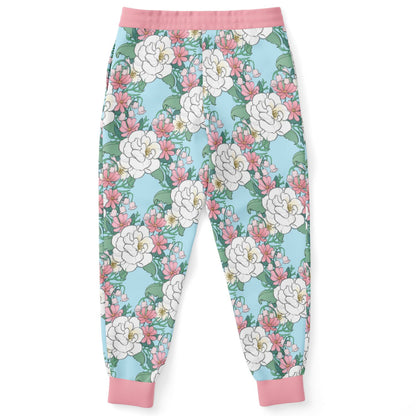 The back of a pair of joggers lying flat.. The joggers' pattern features white wild roses, pink cosmos, and lillies of the valley on a light blue background. it has a pink hem and cuffs.