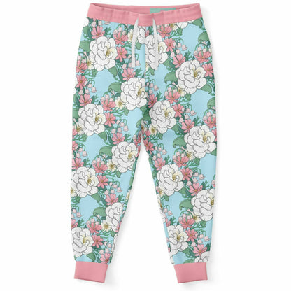 The front of a pair of joggers lying flat.. The joggers' pattern features white wild roses, pink cosmos, and lillies of the valley on a light blue background. it has a pink hem and cuffs.