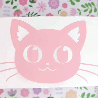 A pink vinyl sticker of a cat with big eyes.