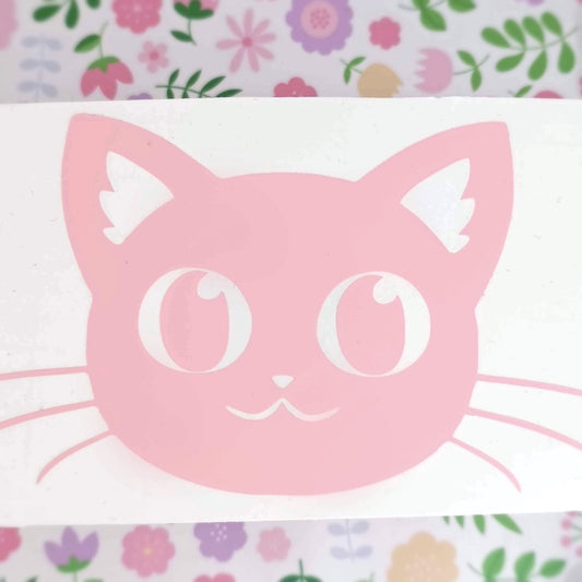 A pink vinyl sticker of a cat with big eyes.